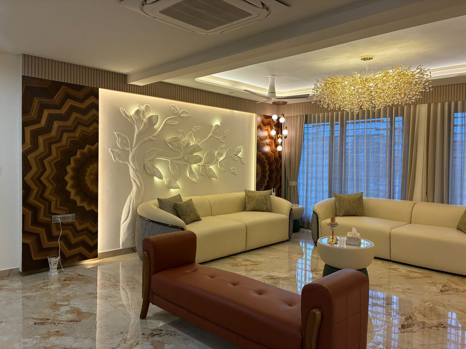 Living room with a carved relief wall, crystal chandelier and cove lighting